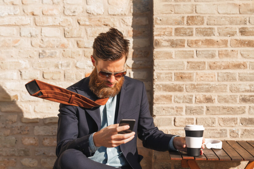 A swedish man is using his smart phone on a coffee break in the city